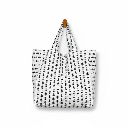 Tote bag with black anchor pattern hanging on a white background